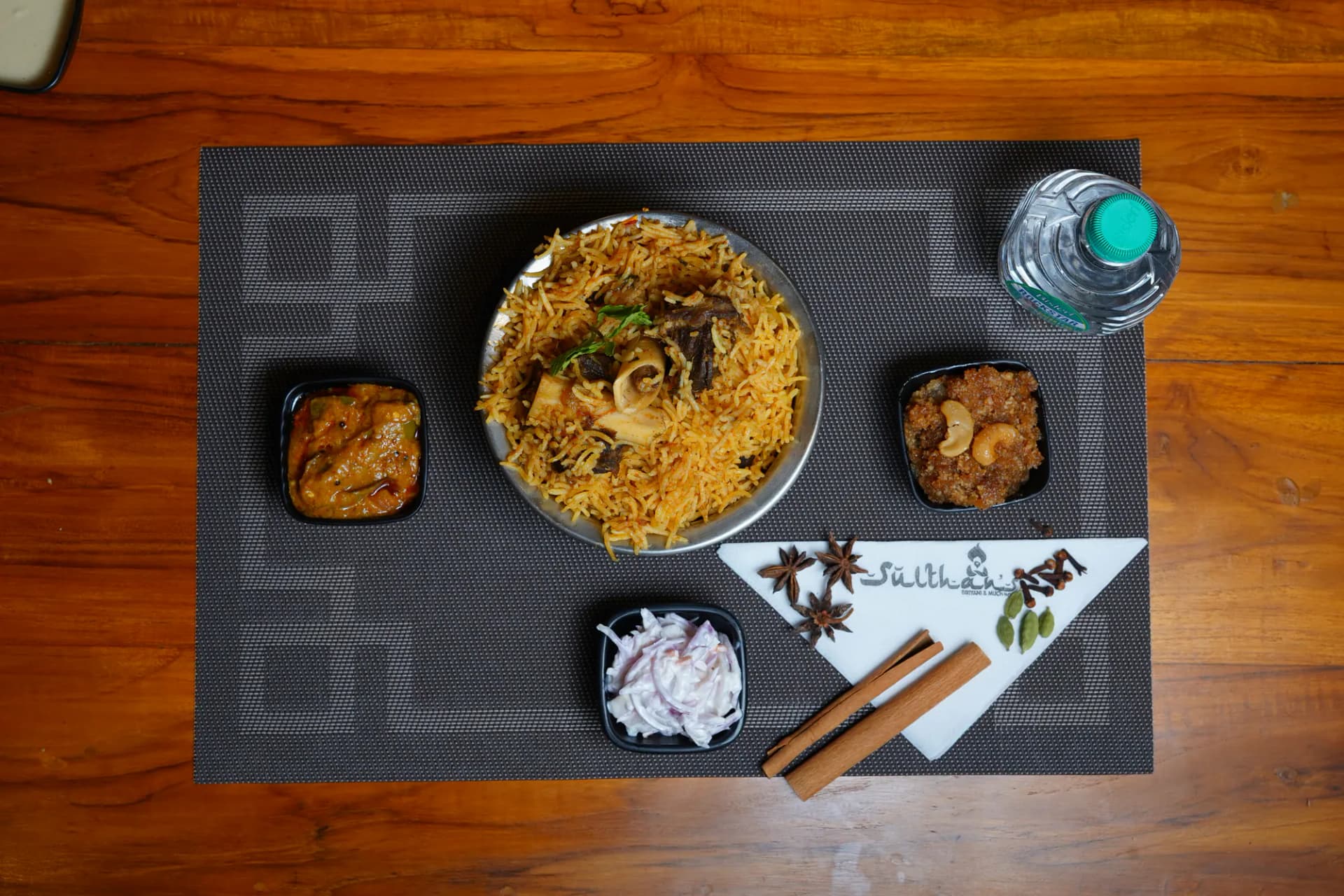 Mutton dum biryani served on a brass plate